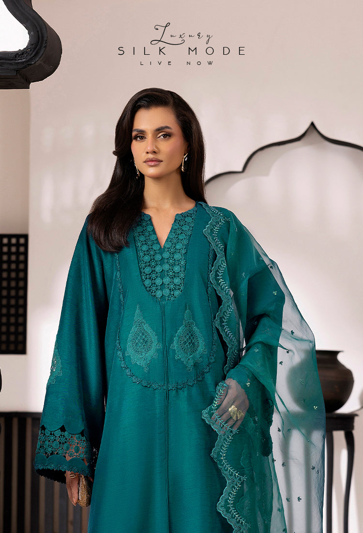 Woman wearing a teal embroidered outfit with 'Luxury Silk Mode' branding.